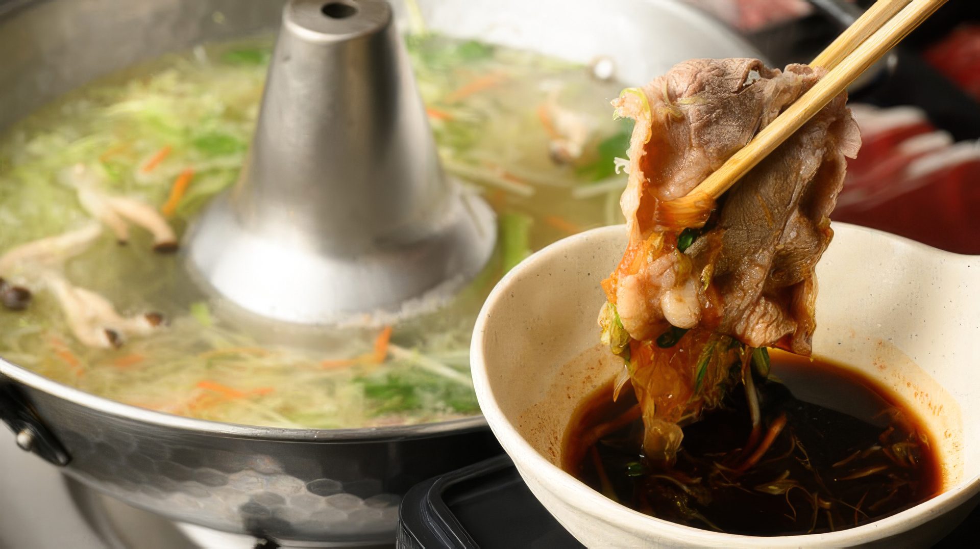 箸でお肉をタレにつけている様子